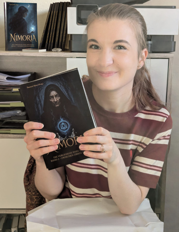 Naomi Krishna hält den 2. Band der Nimoria-Anthologie in den Händen